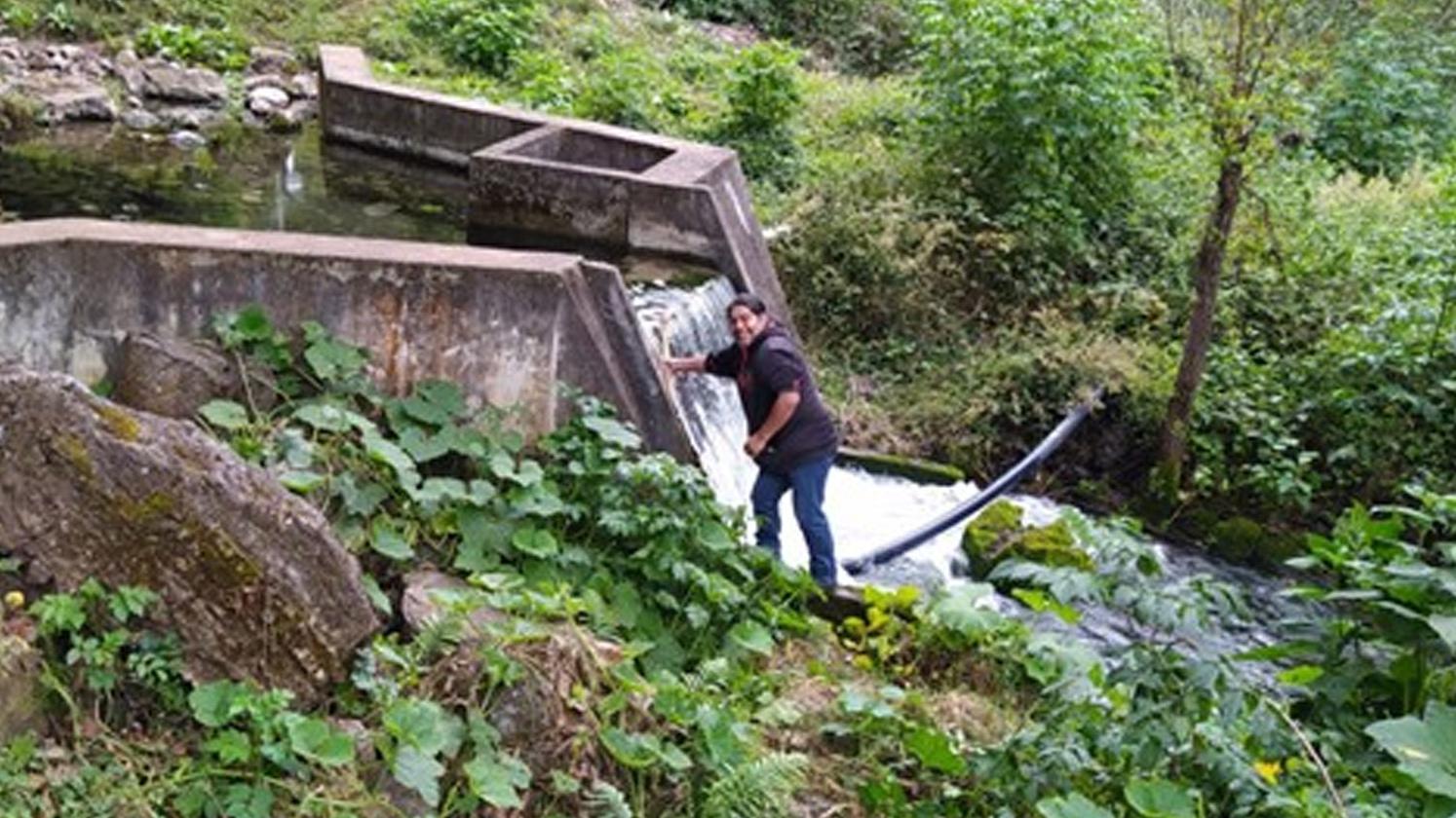 A person standing in front of a small water dam